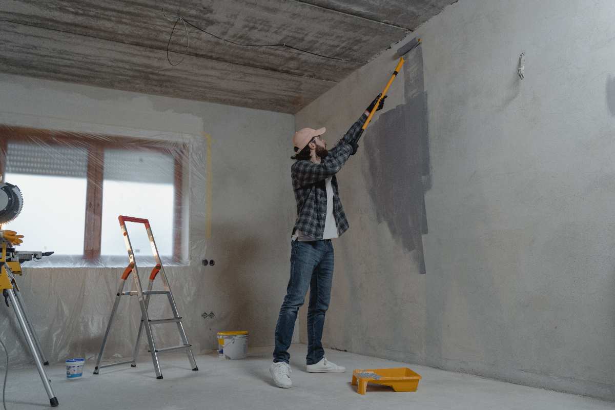 Operaio sta pitturando il muro di una casa da ristrutturare