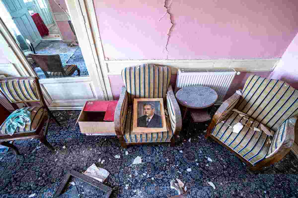 Casa colpita da un terremoto, al centro una poltrona con sopra un quadro