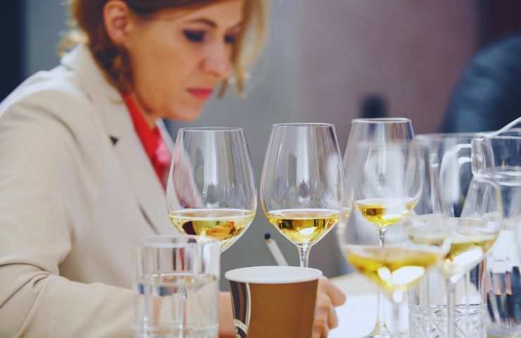 ragazza di fronte a diversi calici di vino bianco pronta a esaminarli