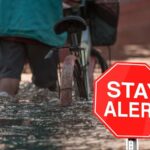 Un ragazzo in bici sotto la pioggia