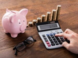 Calcolo dell'Irpef, un salvadanaio, una calcolatrice e diverse monete