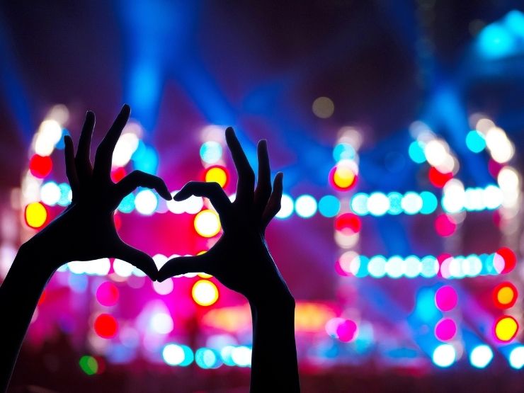 Una ragazza fa un cuore con le mani durante il concerto del suo cantante preferito