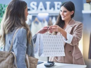 Una commessa dà un sacchetto a una cliente contenente prodotti appena acquistati