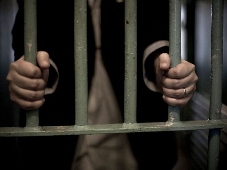 Un detenuto poggia le mani sulle sbarre della sua cella 