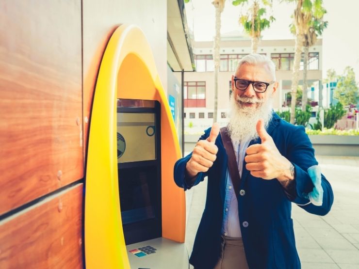 Un pensionato è felice mentre ritira la pensione all'ATM