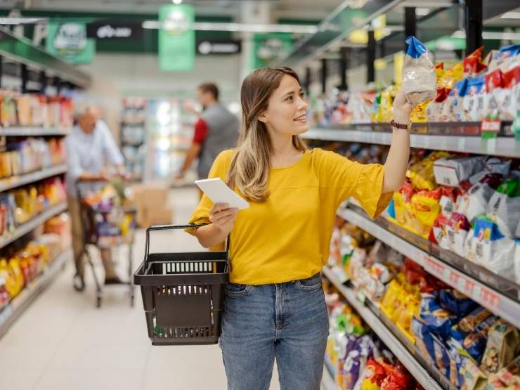 Una ragazza fa la spesa al supermercato con in mano la lista