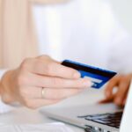 Acquisti online: una donna contempla una carta di credito