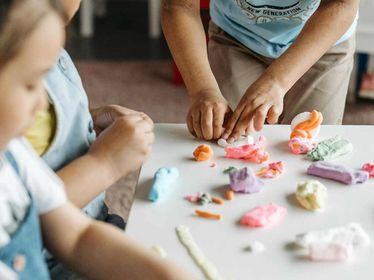 Mani di bimbi su un tavolo con dei giocattoli