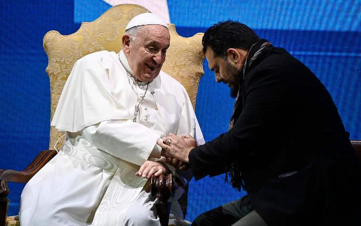 papa francesco con un uomo che gli stringe la mano