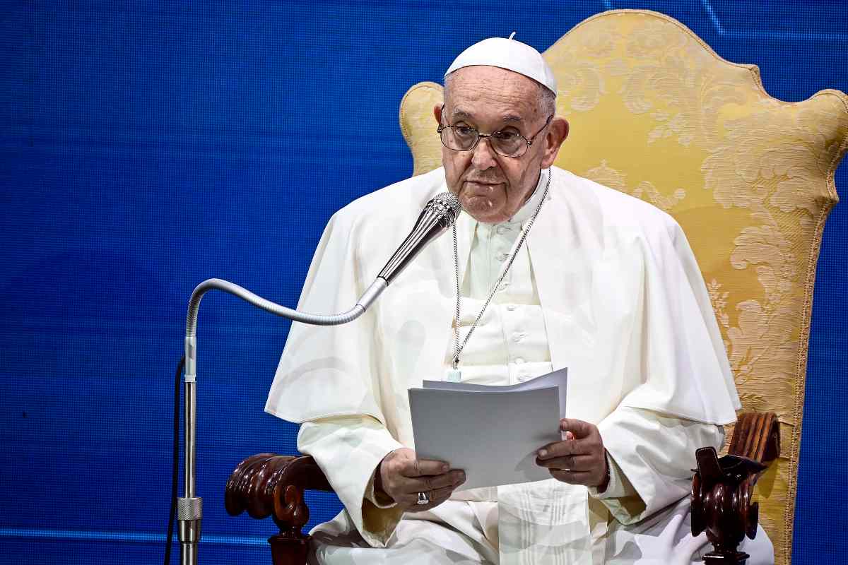 papa francesco seduto con dei fogli in mano