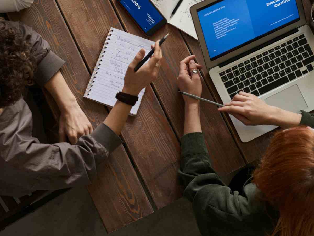 Ragazzi che lavorano con computer e quaderni intorno a una scrivania