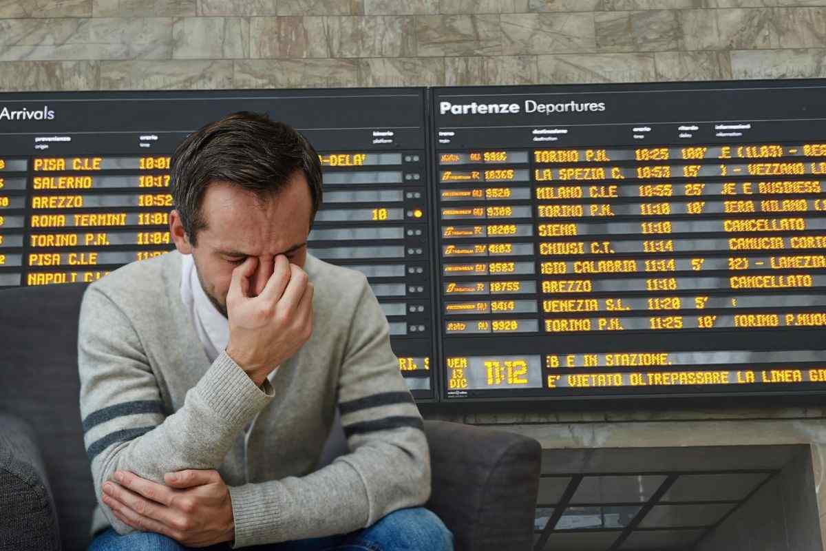 tabellone stazione e un uomo triste