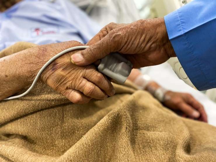 Il medico tiene la mano a un paziente anziano in ospedale