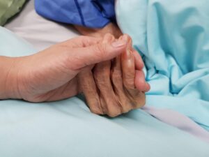Una figlia stringe la mano alla madre anziana in fin di vita