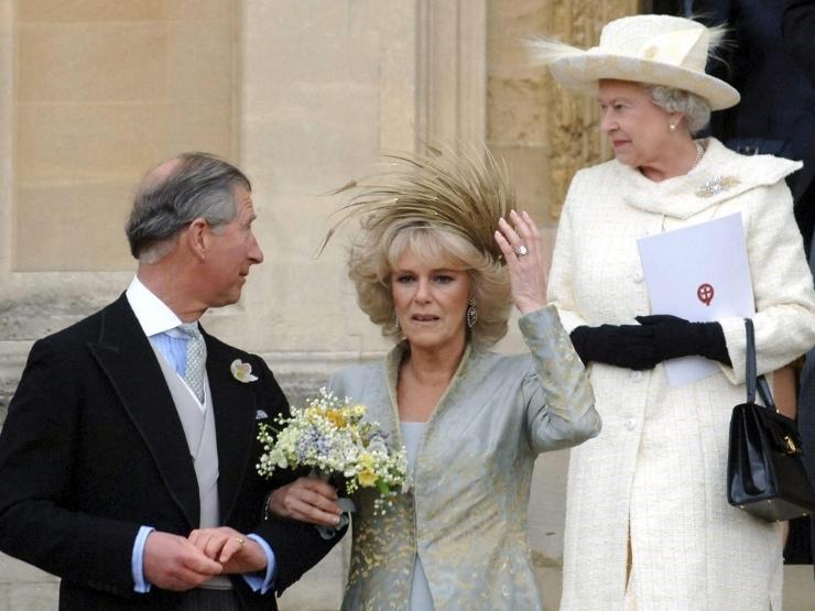 Carlo e Camilla nel giorno del loro matrimonio, sullo sfondo la regina Elisabetta vestita di bianco