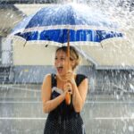Una ragazza sorride sotto la pioggia in primavera