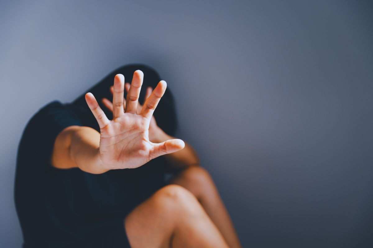 una donna mette la mano avanti per proteggersi