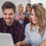Una coppia di giovani sorride mentre lavora al computer