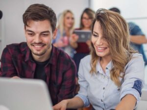 Una coppia di giovani sorride mentre lavora al computer