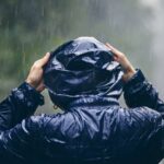Una persona si ripara dalla pioggia con l'impermeabile