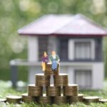 Boom dei mutui, una famiglia seduta su una pila di monete, una casa sullo sfondo