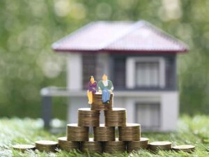 Boom dei mutui, una famiglia seduta su una pila di monete, una casa sullo sfondo