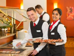 Tre giovani camerieri sorridono mentre lavorano