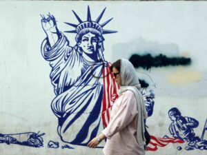 Crisi nucleare tra Iran ed Israele, una donna cammina a Teheran davanti ad un murales