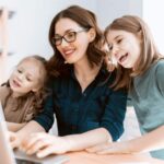 Una madre al computer mentre lavora con le figlie