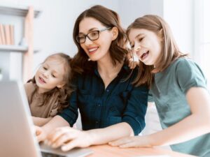 Una madre al computer mentre lavora con le figlie