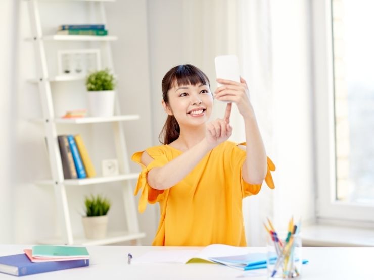 Una ragazza si distrae scattando un selfie mentre studia