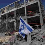 bandiera israele e palazzo distrutto