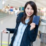 Una ragazza è pronta per partire con i documenti e il trolley