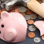 Banche e fallimenti, un martello rompe un salvadanaio a porcellino con monete sparse
