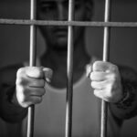 Detenuto in carcere con le mani sulle sbarre della cella