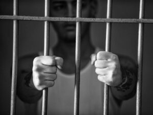 Detenuto in carcere con le mani sulle sbarre della cella
