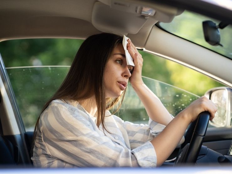 Una donna guida l'auto in estate ed ha molto caldo