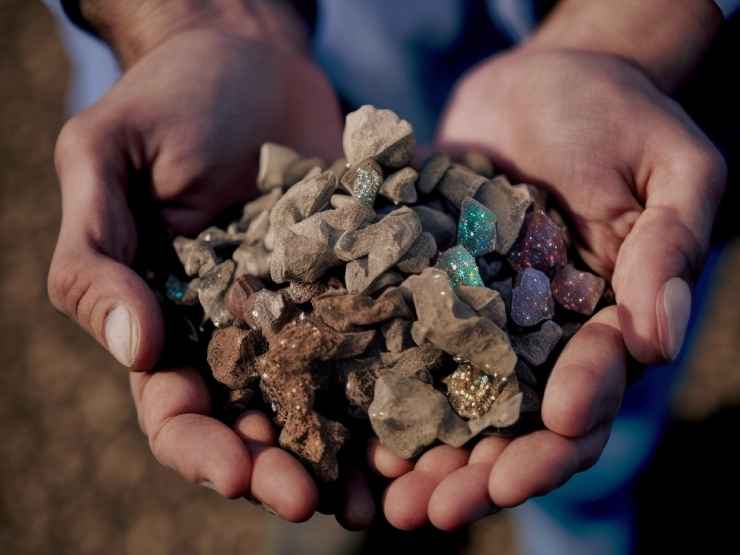 Due mani tengono minerali preziosi e terre rare