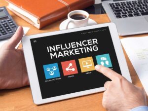 Un tablet con la scritta influencer marketing su una scrivania con una tazzina di caffè