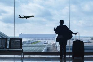 Persona con valigia guarda aereo decollare