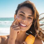Ragazza felice usa la protezione solare in spiaggia