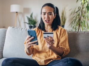 Una ragazza seduta sul divano al computer ha appena scoperto di essere stata truffata online