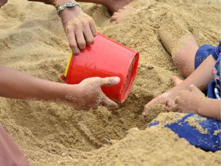 Ragazzi scavano una buca in spiaggia al mare, i pericoli e i consigli