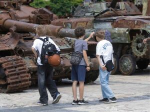 Ragazzini nei pressi di un carrarmato a Kiev, attacchi massicci della Russia contro l'Ucraina
