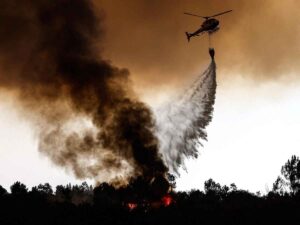 Un elicottero prova a spegnere un incendio boschivo, polemica sui costi