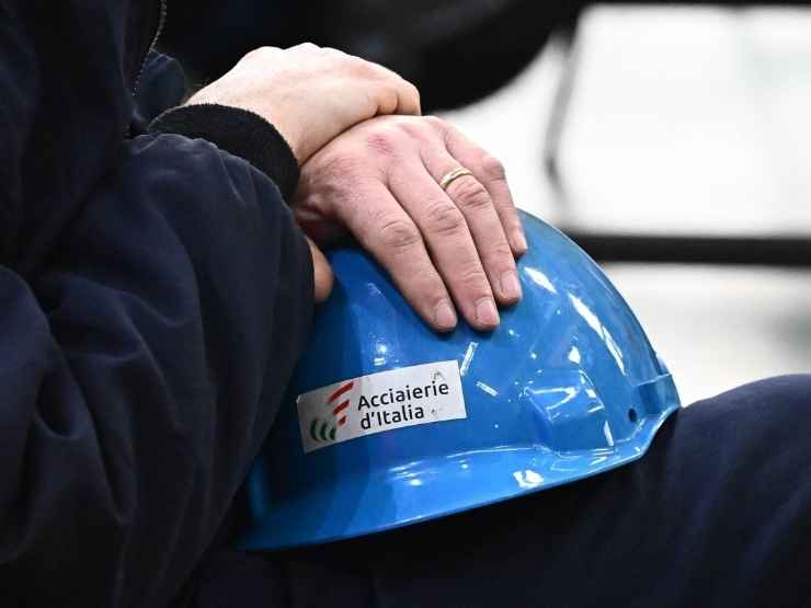 Un operaio mantiene il suo caschetto della fabbrica Acciaierie d'Italia