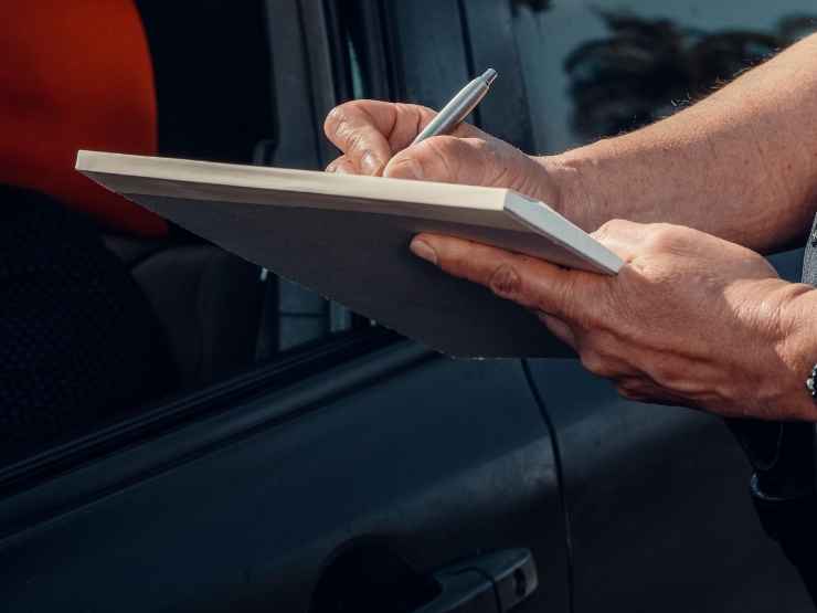 Un poliziotto compila una multa ad un'automobilista indisciplinato