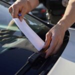Un poliziotto infila una multa sotto il tergicristallo di un'auto