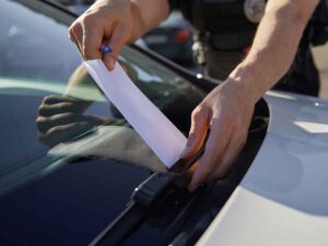 Un poliziotto infila una multa sotto il tergicristallo di un'auto