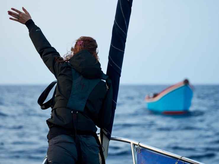Una volontaria di una ong richiama l'attenzione di un barcone carico di migranti nel mar Mediterraneo